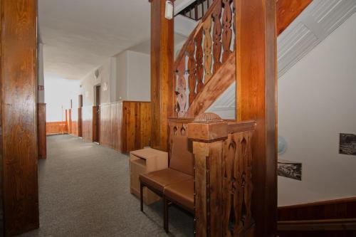 a hallway with a wooden staircase with a brown chair at Penzion Betlém in Janske Lazne