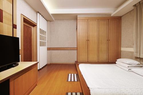 a small room with a bed and a television at 薇風情汽車旅館 - 台南館 in Liujia