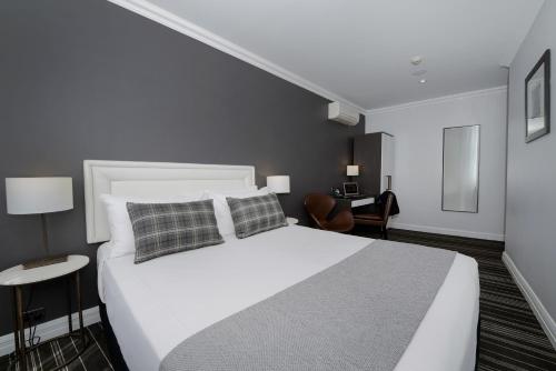 a bedroom with a large white bed and a desk at Perouse Randwick by Sydney Lodges in Sydney