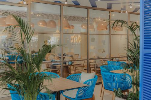 a restaurant with blue chairs and tables and glass walls at Iberostar Selection Albufera Playa All Inclusive in Playa de Muro