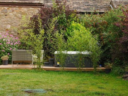 a garden with two benches and some plants at The Old Bulls Head in Chapel en le Frith