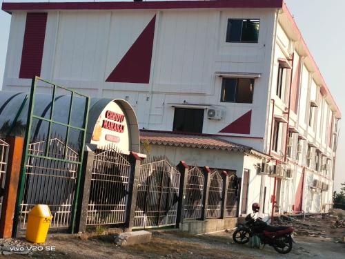 a man sitting on a motorcycle in front of a building at Maa Paradise World in Alīpur Duār