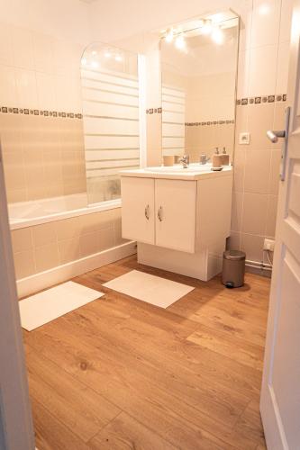une salle de bain avec un lavabo, une baignoire et un miroir dans l'établissement Casa Saint Denis, à Labenne