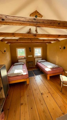 two beds in a room with wooden floors at Pension Schneidenbach in Reichenbach im Vogtland