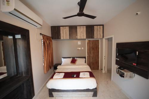 a small bedroom with a bed and a flat screen tv at Shanthi Service Apartment in Madurai