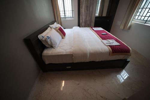 a bedroom with a bed with white sheets and pillows at Shanthi Service Apartment in Madurai