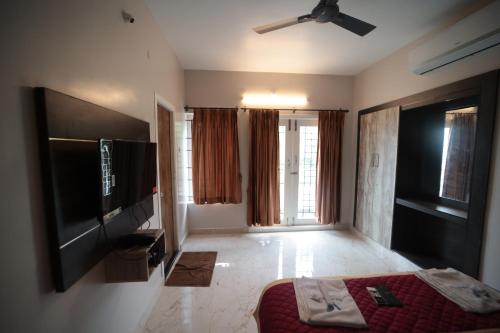 a bedroom with a flat screen tv and a bed at Shanthi Service Apartment in Madurai