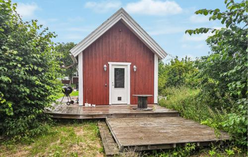 a red house with a wooden deck with a table at 1 Bedroom Amazing Home In Blomstermåla in Blomstermåla