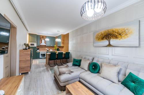 a living room with a white couch and green pillows at Cozy Collection Apartments at Adora Park in Arad