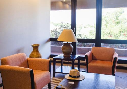 a living room with two chairs and a table with a lamp at Evora Hotel in Évora
