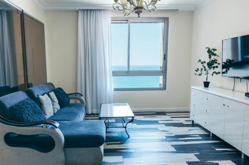 a living room with a blue couch and a window at Almog Haifa Israel Apartments מגדלי חוף הכרמל in Haifa