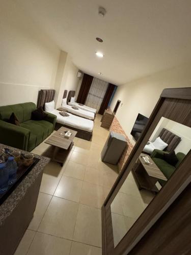 a large living room with a green couch and tables at El RAYYAN HOTEL SUITES in Amman