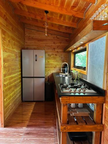 a kitchen with a stainless steel refrigerator in a log cabin at Cabaña Oregon Pucura in Panguipulli