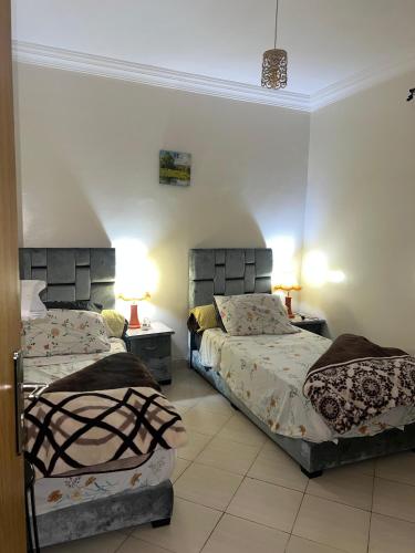 a bedroom with two beds and two lamps on tables at Appartement au centre ville pres de la plage in El Jadida