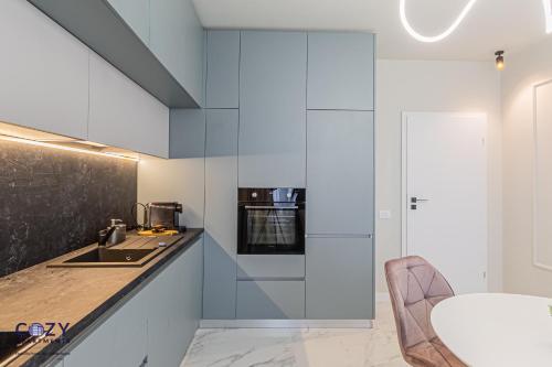 a kitchen with white cabinets and a counter with a sink at COZY Aparthotel - Premium Suites and Studios in Braşov