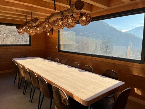 a long table and chairs in a room with a large window at La Biche in Saint-Martin-sur-le-Chambre