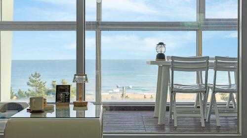 a room with a table and two chairs and a view of the beach at Yangyang Oceanvibe in Yangyang