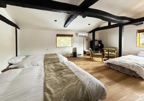 a bedroom with two beds and a table and a chair at 白馬の黒馬　DarkHorse @Hakuba in Hakuba