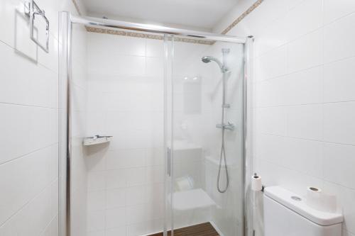 a white bathroom with a shower and a sink at Casa Menvil in Sant Jordi de Cercs