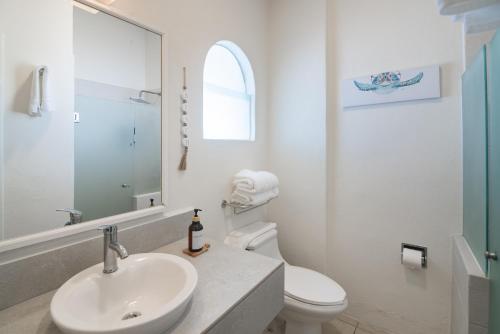 a white bathroom with a sink and a toilet at Vista al Mar, Terraza y Albercas in Manzanillo