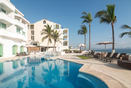 a swimming pool in front of a building with palm trees at Vista al Mar, Terraza y Albercas in Manzanillo