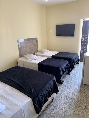 three beds in a room with a tv on the wall at Alvorada Palace Hotel de Poços in Poços de Caldas