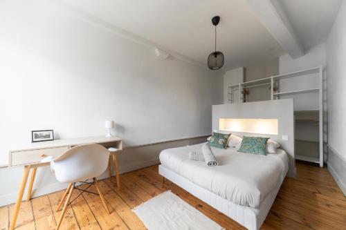une chambre blanche avec un lit et un bureau dans l'établissement Le Ballainvilliers - Appartement cœur de ville, à Clermont-Ferrand