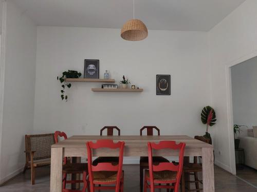 a dining room with a wooden table and red chairs at Maison avec terrasse Bordeaux Chartrons in Bordeaux