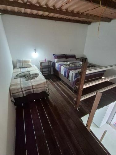 two beds in a room with wooden floors at Chalé do galo in São Domingos