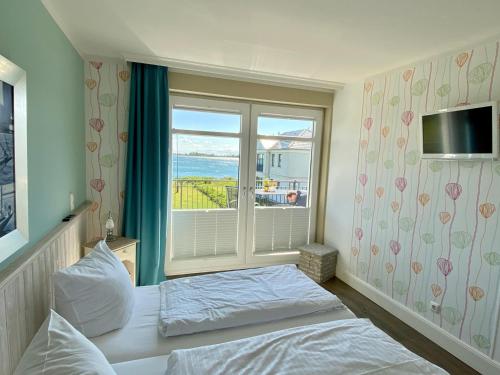une chambre avec un lit et une grande fenêtre dans l'établissement Ferienresidenz Haus Vogelflug Fehmarn-Ostseeferien Strandresidenz Vogelflug 141 App 4 Meerblick, à Fehmarn