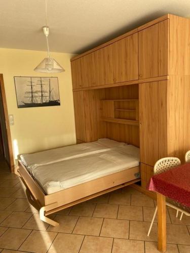 a bed in a room with a wooden cabinet at FeWo Schulze in Fehmarn