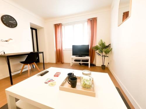 a living room with a white table and a television at Hyper center - 10'St Nazaire in Trignac