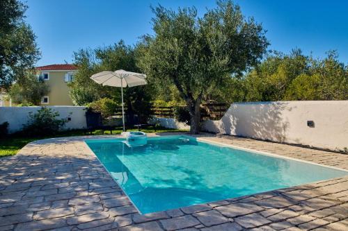 a swimming pool with an umbrella in a yard at Villa Ariadne Periyali in Katastárion