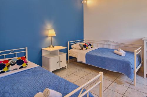 two beds in a room with blue walls at Villa Ariadne Periyali in Katastárion