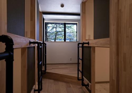 a hallway with a window in a room with wooden walls at 白馬の黒馬　DarkHorse @Hakuba in Hakuba