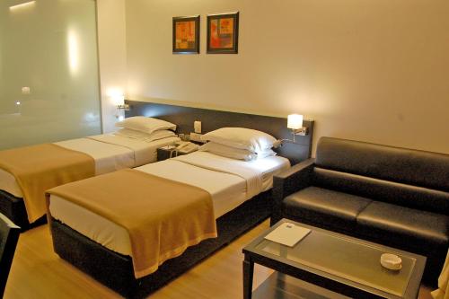 a hotel room with two beds and a couch at Comfort Inn Sunset in Ahmedabad