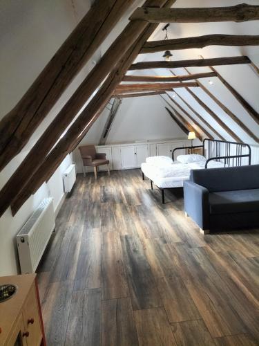 a attic room with two beds and a couch at Vakantiehuis Ganderhoeve in Gaanderen