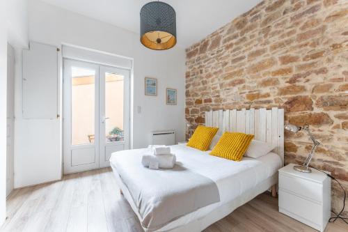 une chambre avec un lit blanc et un mur de briques dans l'établissement Moma - Au cœur du quartier Vaise, à Lyon