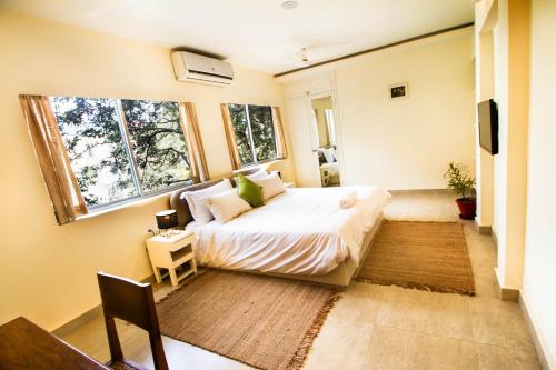 a bedroom with a bed and two windows at Anara Service Apartments - Greater Kailash Part II in New Delhi