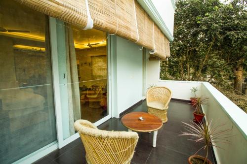 a porch with wicker chairs and a wooden table at Anara Service Apartments - Greater Kailash Part II in New Delhi