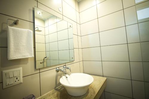 a white bathroom with a sink and a mirror at Anara Service Apartments - Greater Kailash Part II in New Delhi