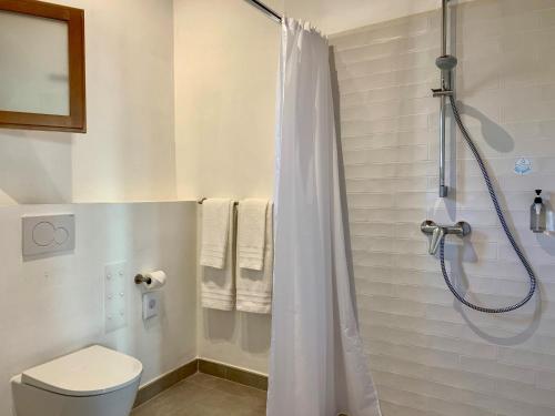 a bathroom with a shower curtain and a toilet at Blue Door Mallorca in Caʼs Concos