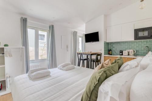une chambre blanche avec un lit et une cuisine dans l'établissement Charming little house in th heart of Batignolles, à Paris