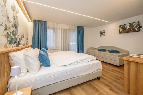 a bedroom with a white bed and a couch at Hotel Des Roses in Antey-Saint-André