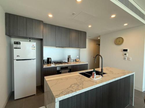 a kitchen with a white refrigerator and a counter top at 2BR apartment close to Accor Stadium in Sydney