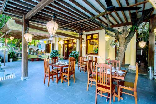 a restaurant with a table and chairs and a tree at Thanh Van 1 Hotel in Hoi An