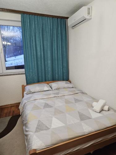 a bedroom with a bed with a green curtain and a window at Amaya Home Sarajevo in Vogošća