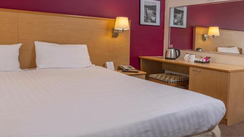 a hotel room with a large bed and a mirror at Best Western The Dartmouth Hotel, Golf & Spa in Dartmouth