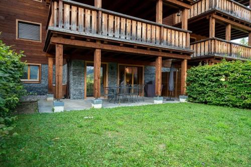 a house with a deck and a lawn in front of it at Terra Nostra A03 in Gryon