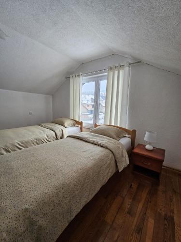 two beds in a room with a window at Amaya Home Sarajevo in Vogošća